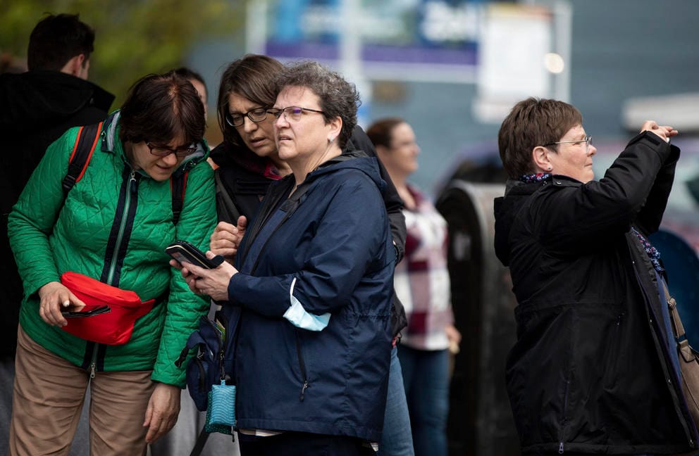 a group of women look at a phone with confused faces