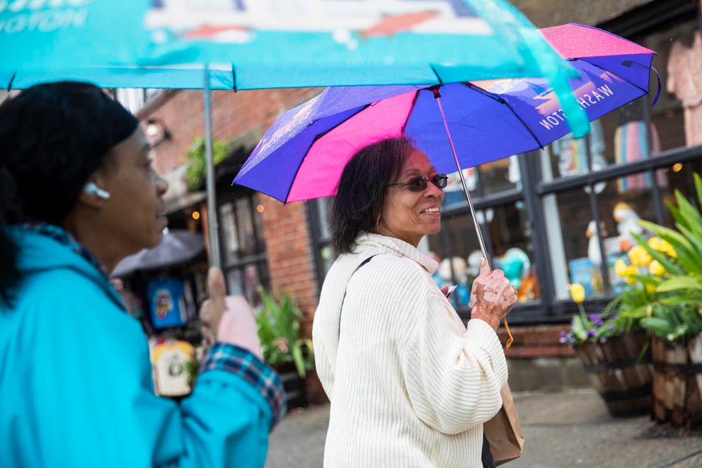 Two women hold colorful umbrellas