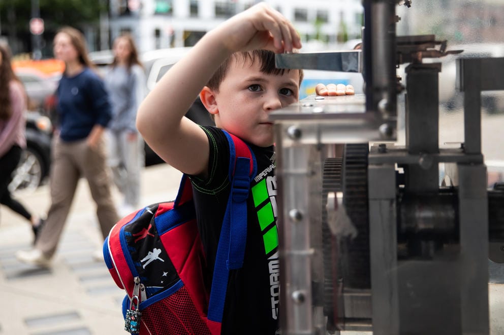 A close up of a boy putting a coin into a souvenir machine