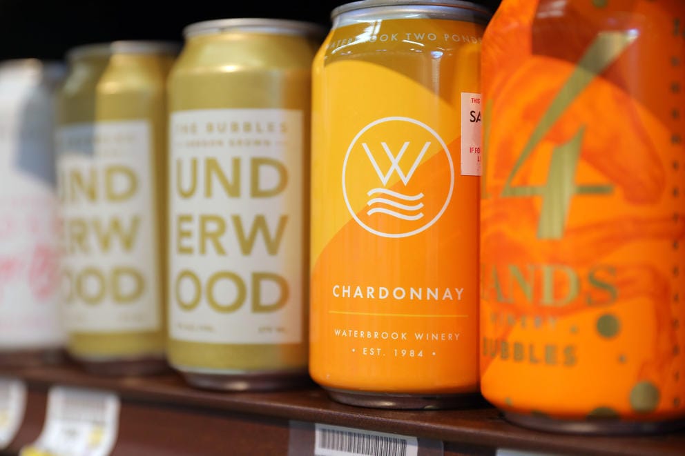 A row of cans from several wineries at the grocery store.