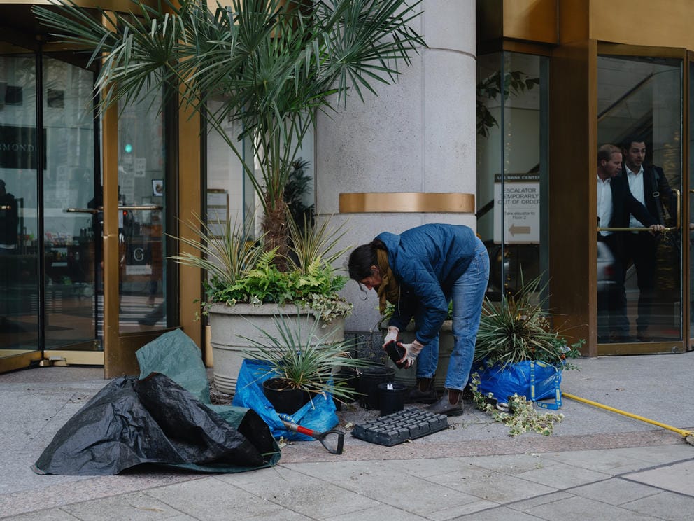 a woman tends to pots of plants on the street
