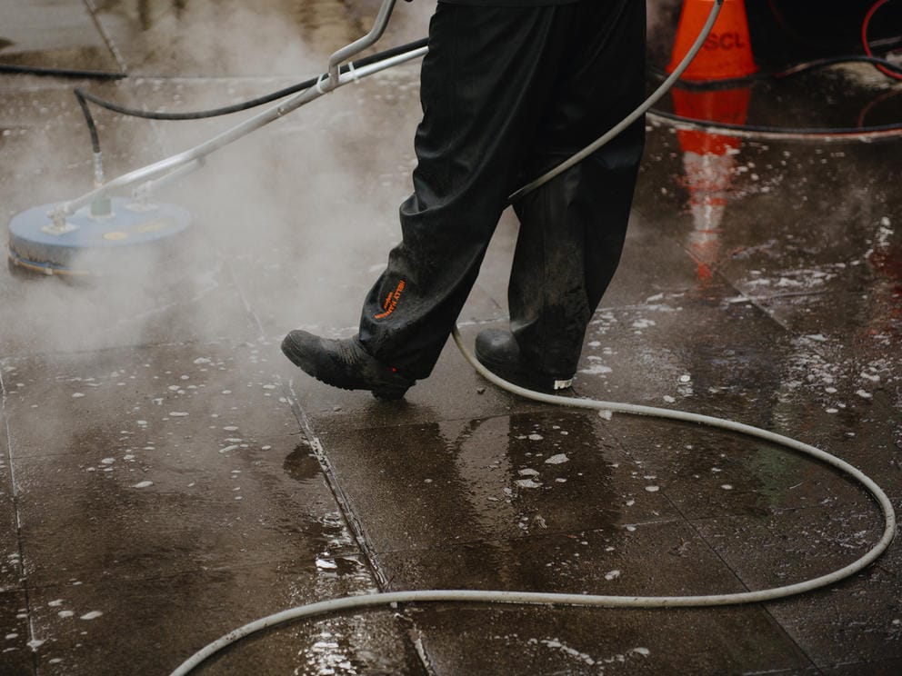 a man scrubbing the sidewalk with a powerwasher