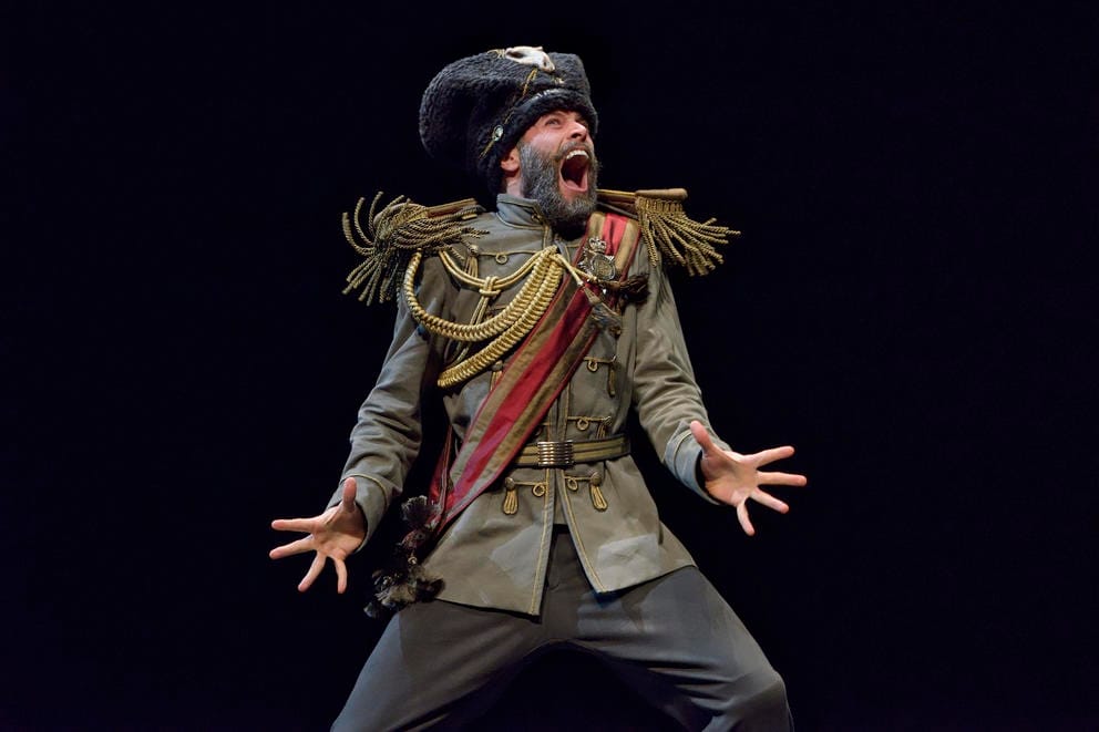 a man on stage in an elaborate general's uniform, his mouth wide open