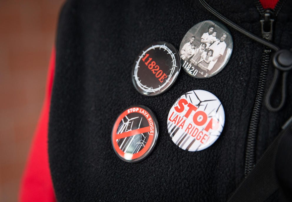 Eugene Tagawa wears pins with his family’s photo and the number tag for his family