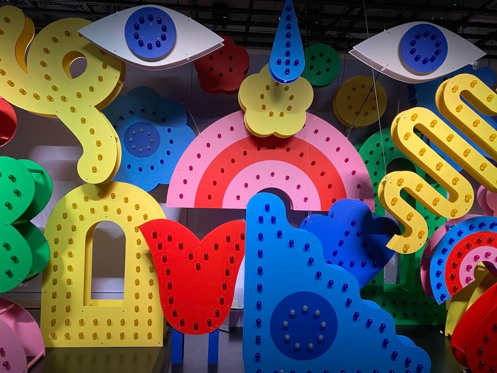 an art installation with many shapes with light bulbs and big blue eyes at the top