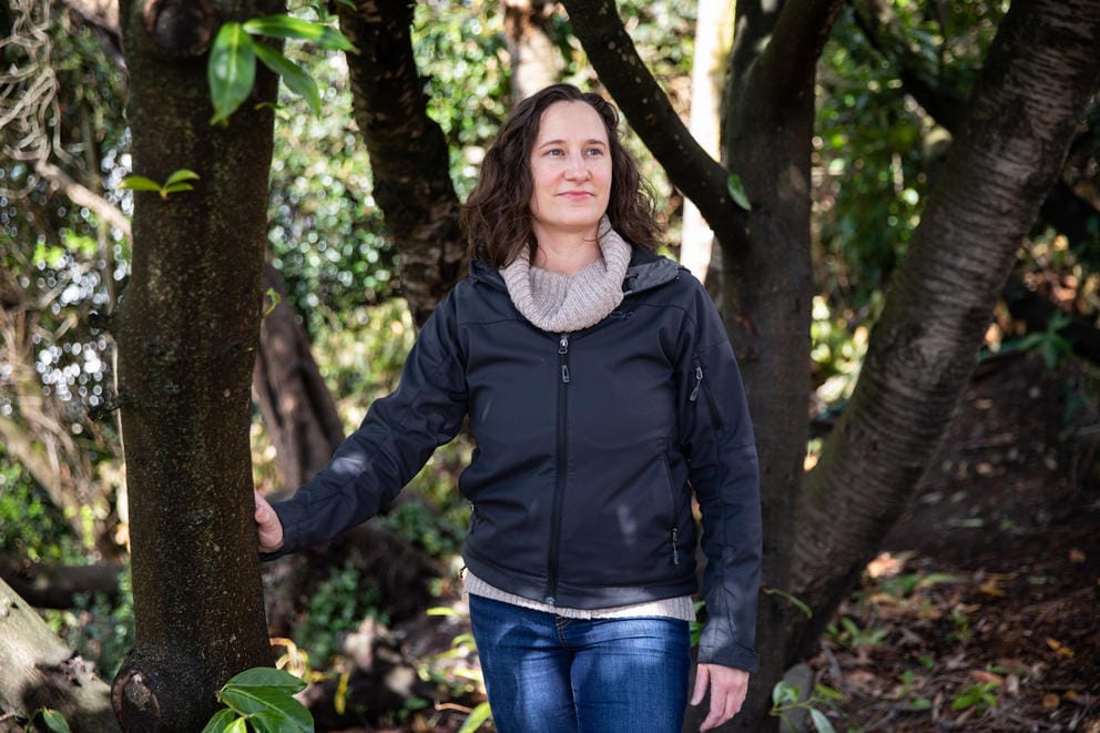 A woman stands between tree branches