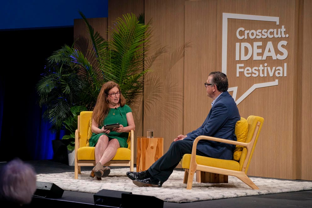 Two people chat on stage in front of an audience