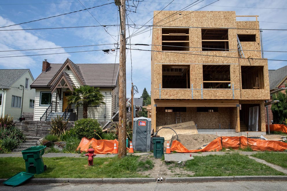 a partially completed townhome next to a single family home