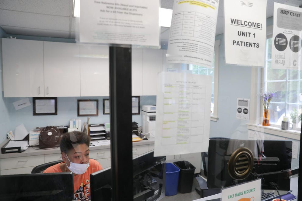 a woman works at a desk behind a plexiglass window