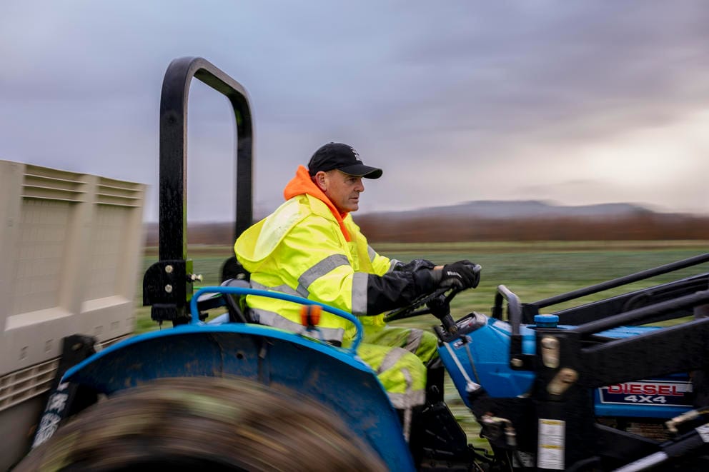 Pastor Jim Eichner drives a tractor during a collard greens harvest at Food Bank Farm.