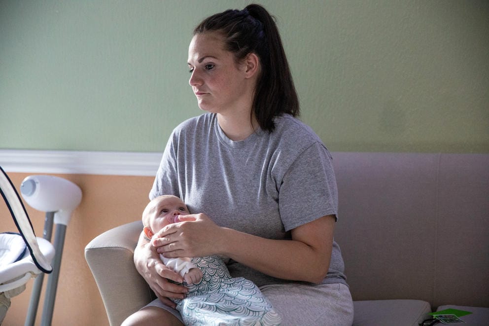 Marie Haller holds her newborn Dahlia on a couch