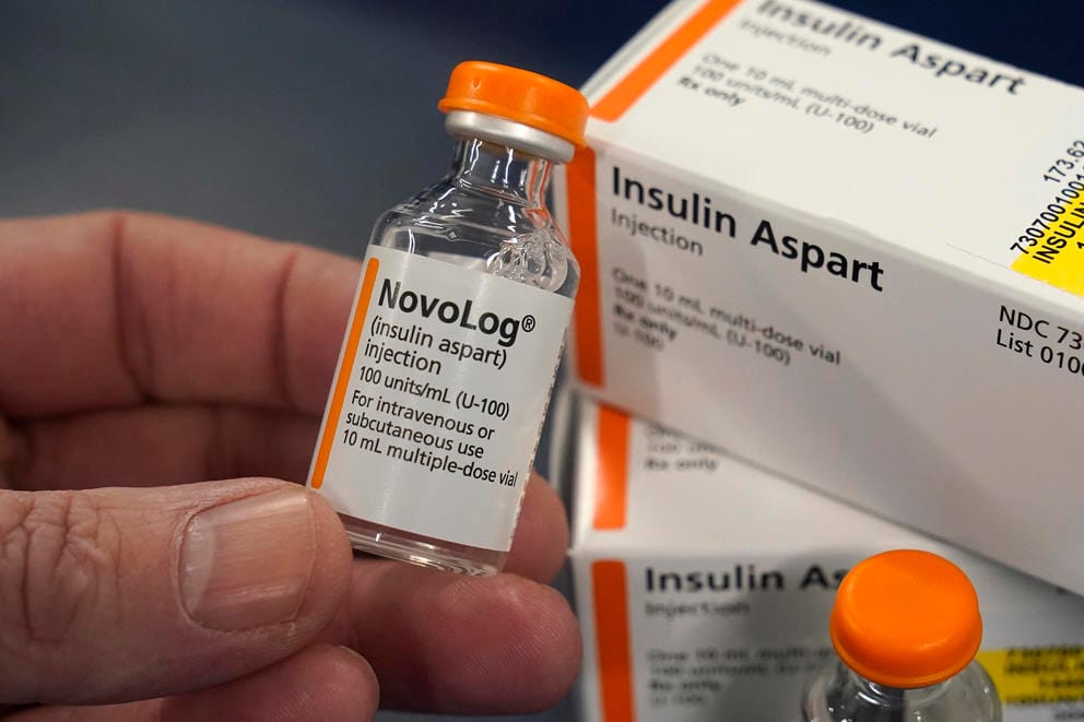 A close up of a hand holding a vial of insulin