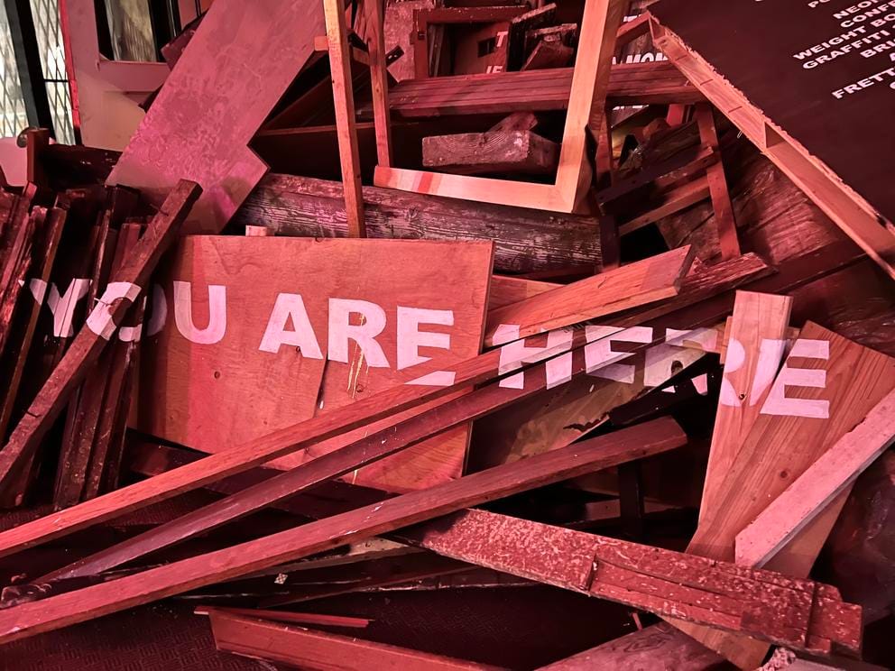 photo of slats of wood painted with the words You Are Here