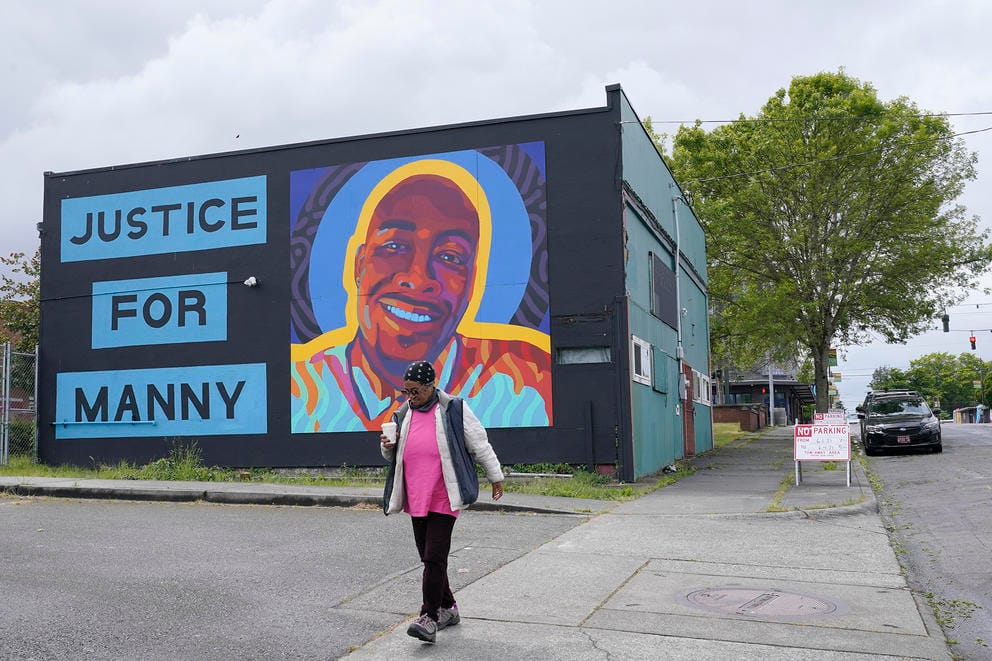 A woman walks past a mural honoring Manuel