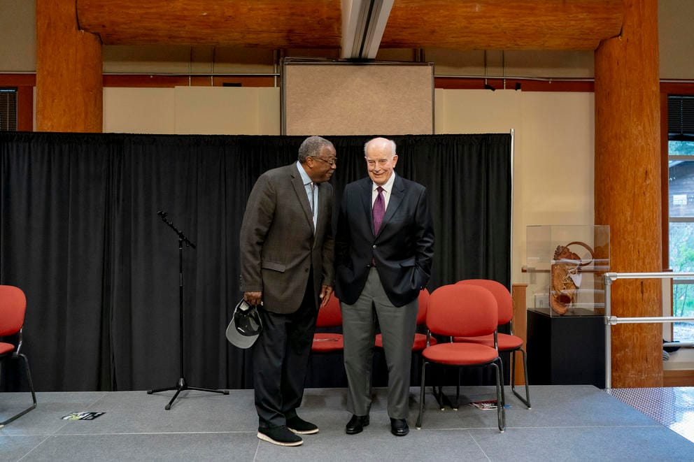 Two people talk to each other while standing on a stage.