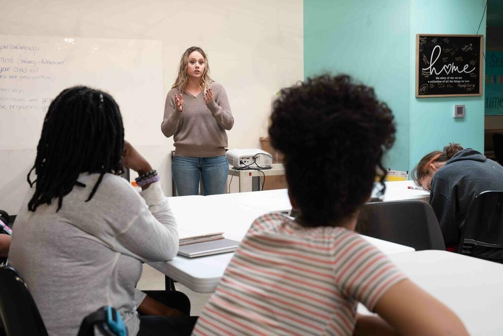 A person leads a class from the front of a classroom.
