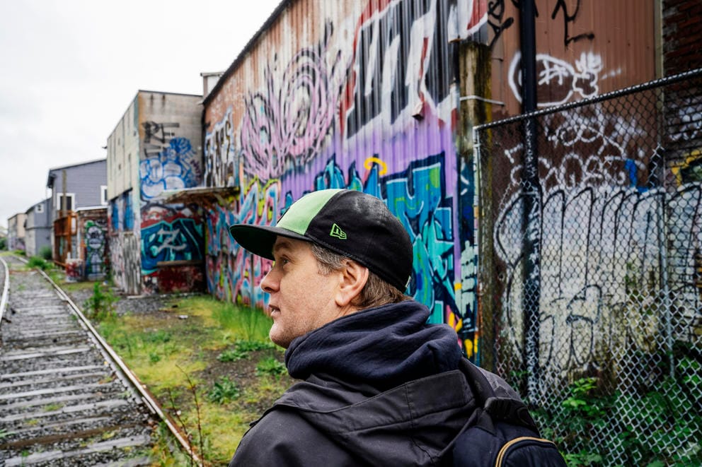 A man walks past a wall of graffiti