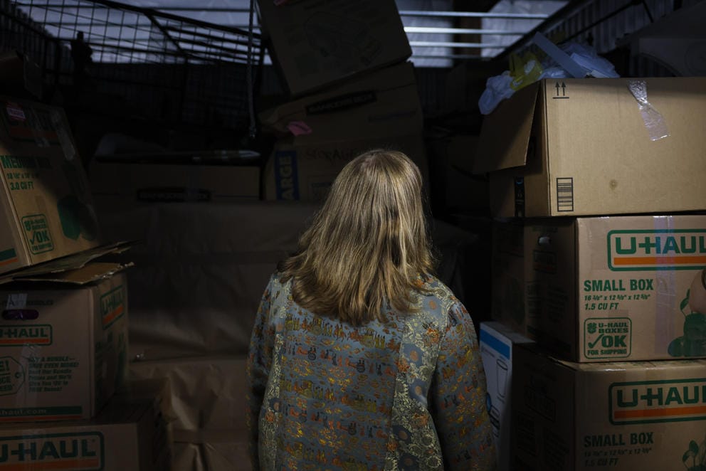 a woman looks into a storage unit filled with boxes