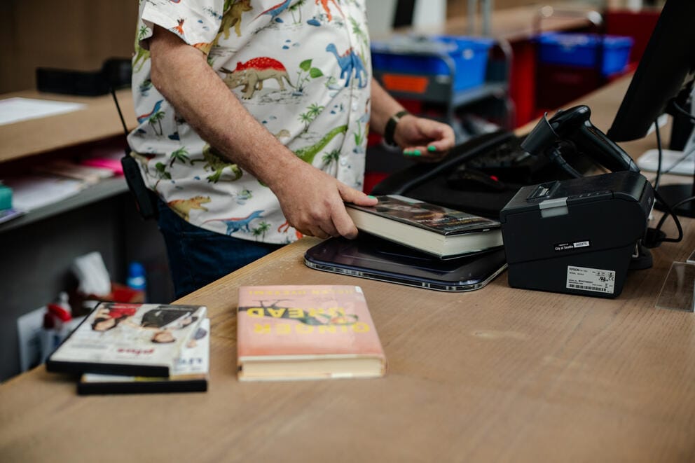 An employee checks in books through a scanner