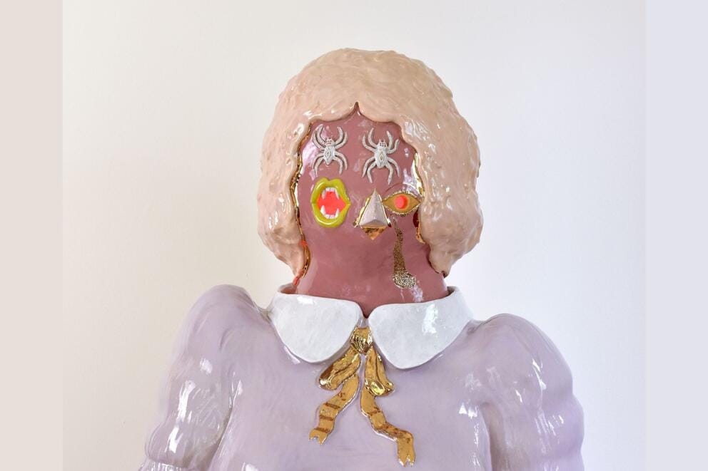 an abstract ceramic figure of a woman wearing a prim pastel blouse, her eyes are spiders