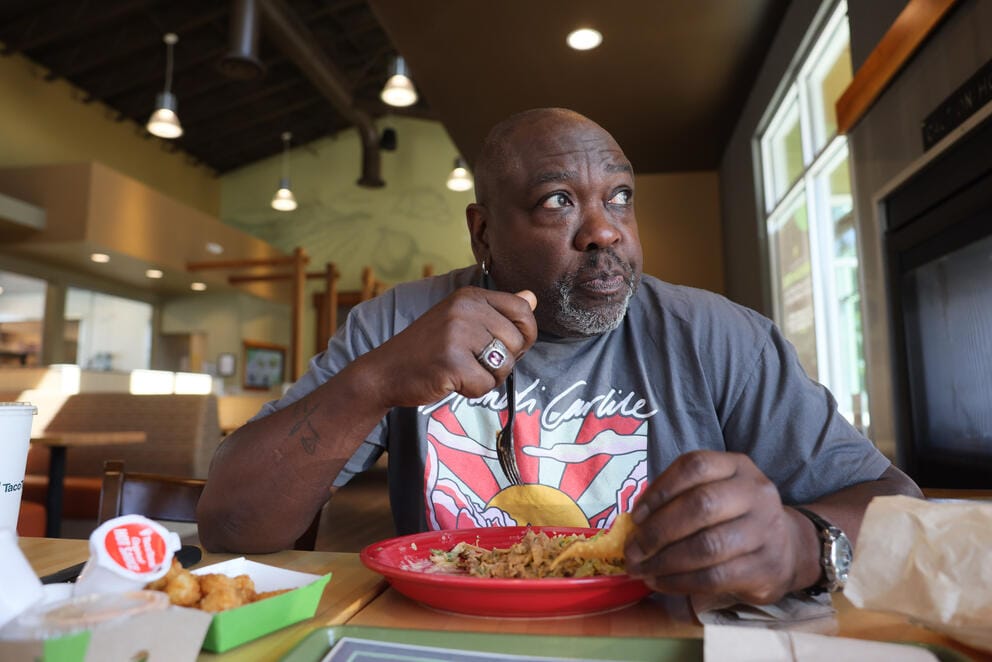A man holds a fork over a plate of food in a taco restaurant