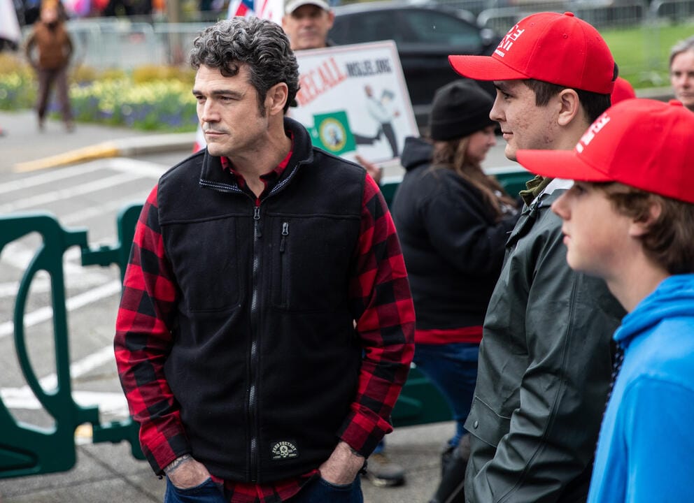 Joe Kent stands at a rally with men in red hats