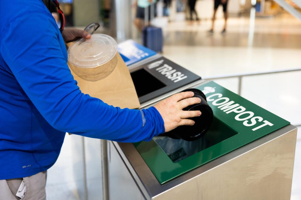 A passenger throws away compostable items.