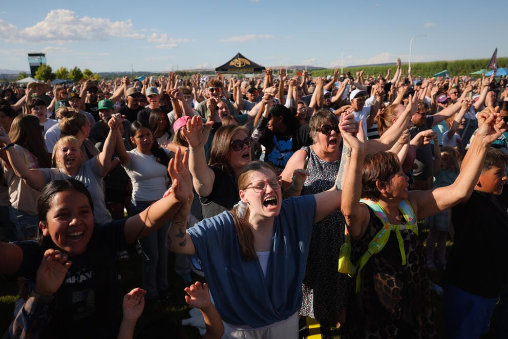 A large group of people raise their arms and sign
