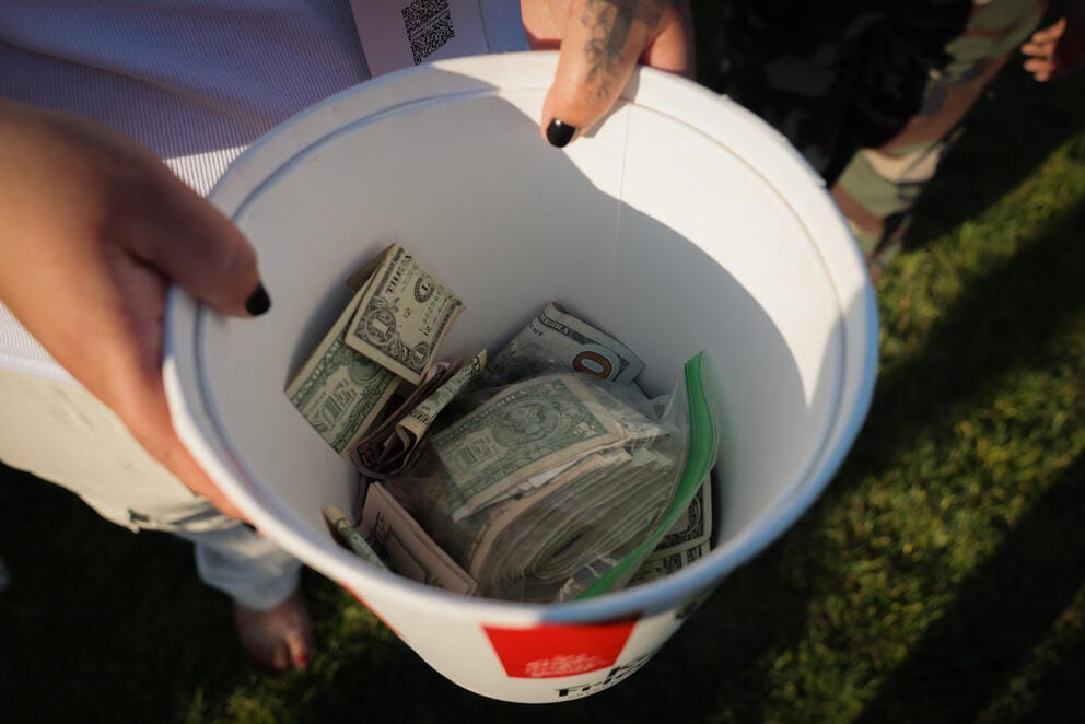 hands hold a bucket full of cash