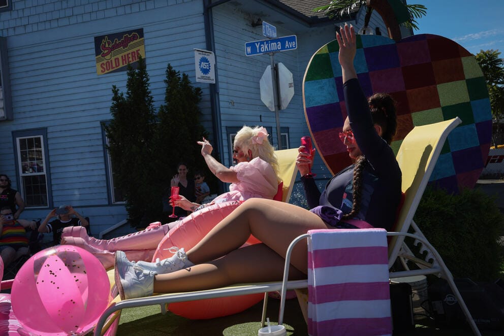 Drag queens wave to onlookers from their float