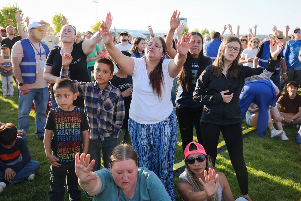 A crowd of people raise their hands up