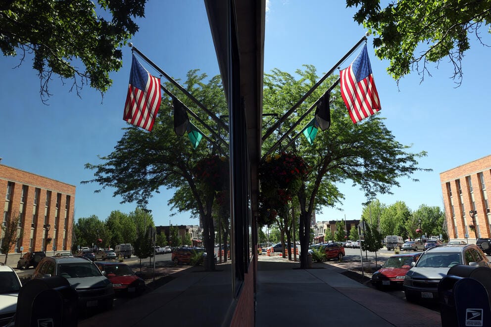 An American flag is reflected in the window of the Yakima City Hall building