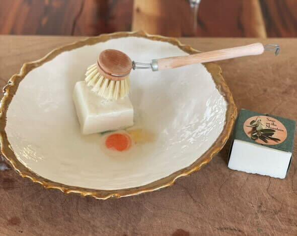 A scrub brush on top of a bar of soap