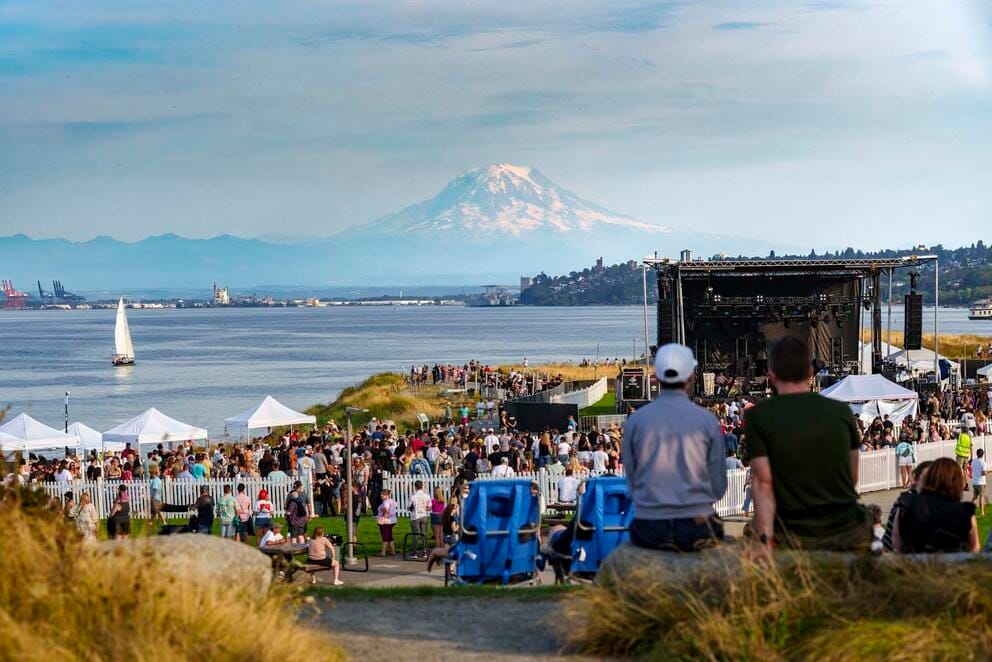 photo of an outdoor concert venue on a hillside; in the distance is a body of water and a huge snowy mountain