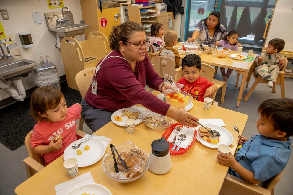 A teacher feeds students during lunch.