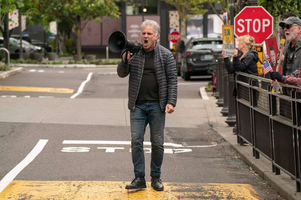 A person talks on a bullhorn while standing in a street.