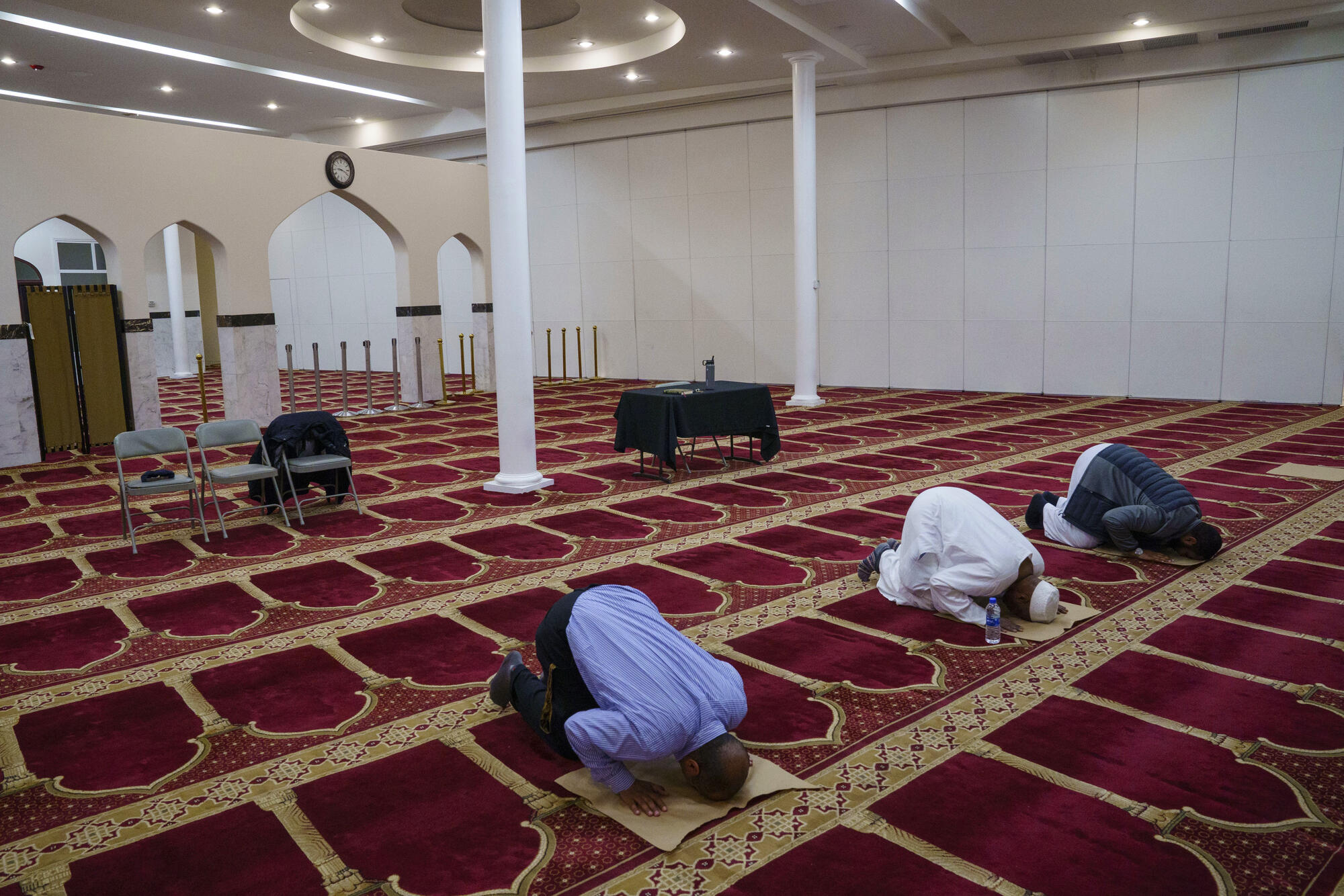 three men praying in mosque