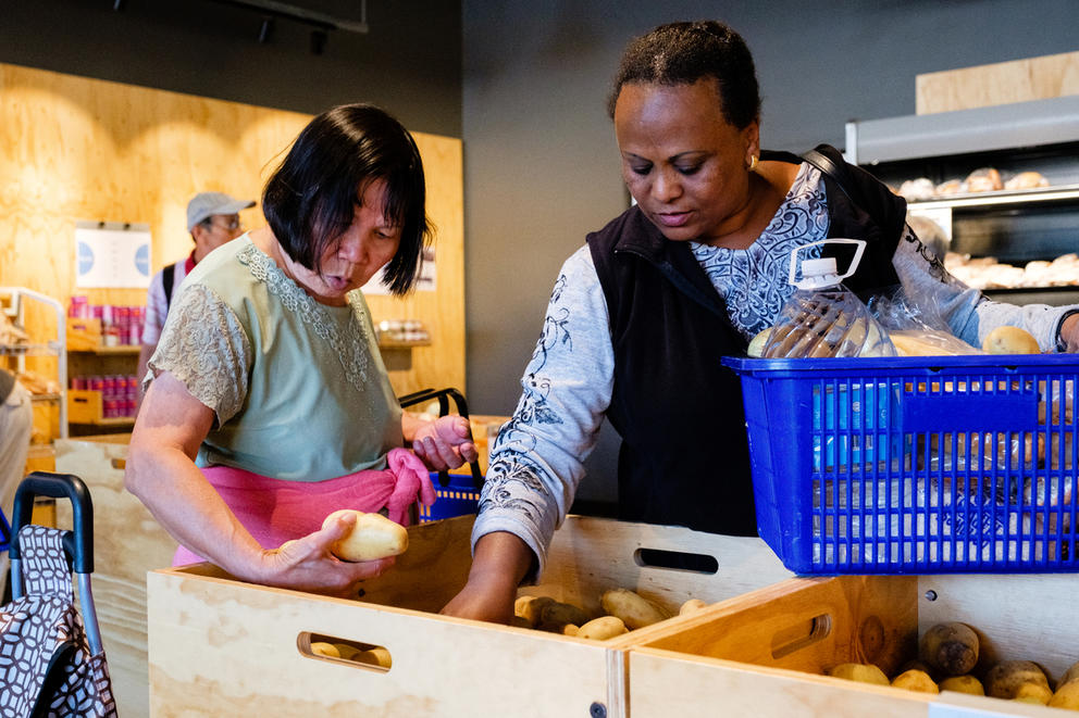 Two people examine potatoes inside a store