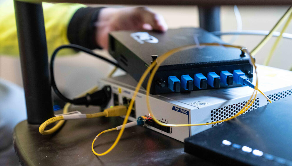 A small black network terminal box is shown with yellow and black cables coming out.