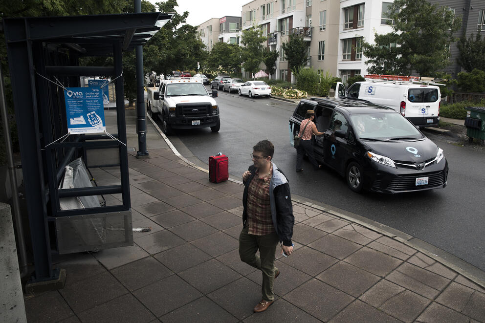 two people unload from a van at a light rail station