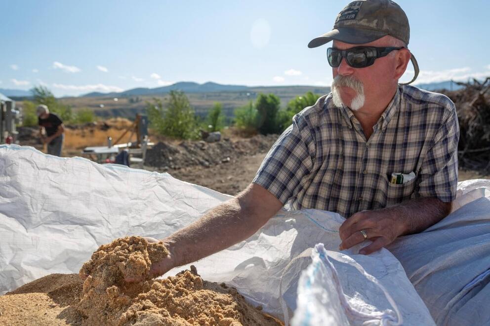 A man in sunglasses holds a handful of sawdust