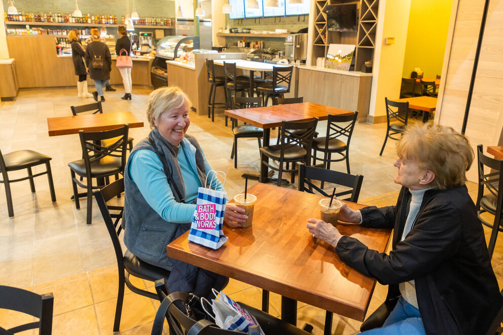 Two women sitting at a table in mall cafe 