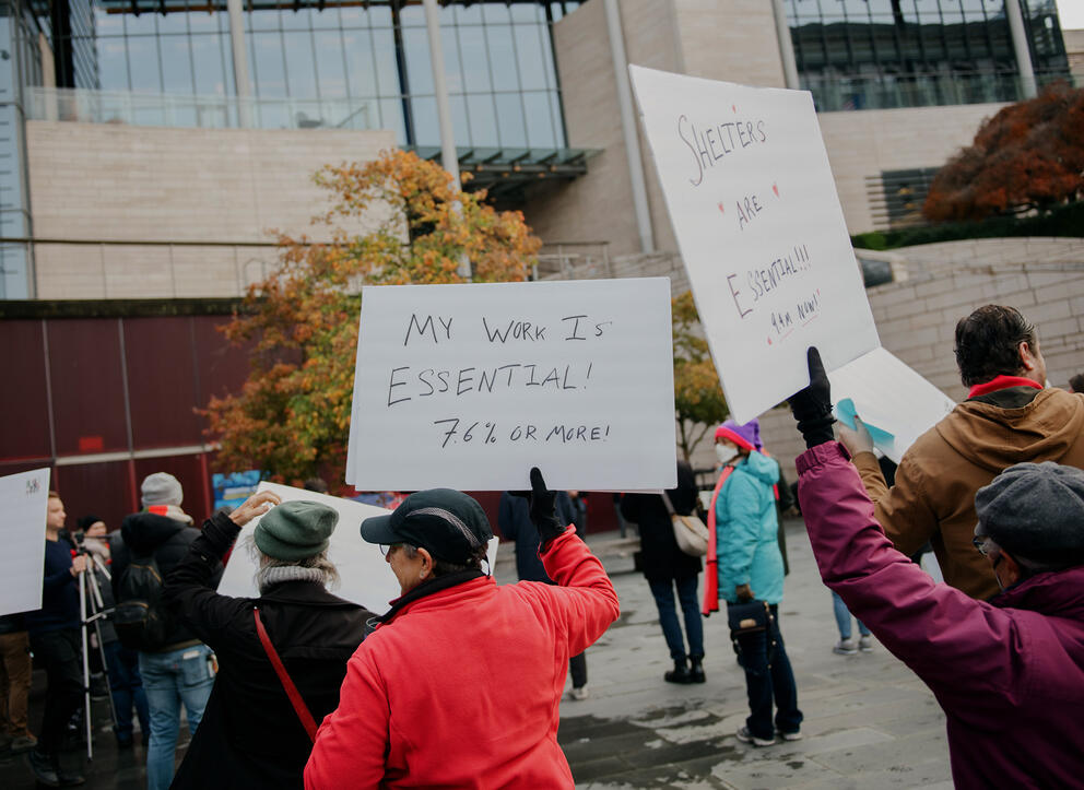 a group of people hold signs at a rally outside seattle city hall