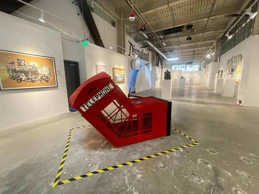 A red telephone booth curved in two, pick-axed in the middle. 