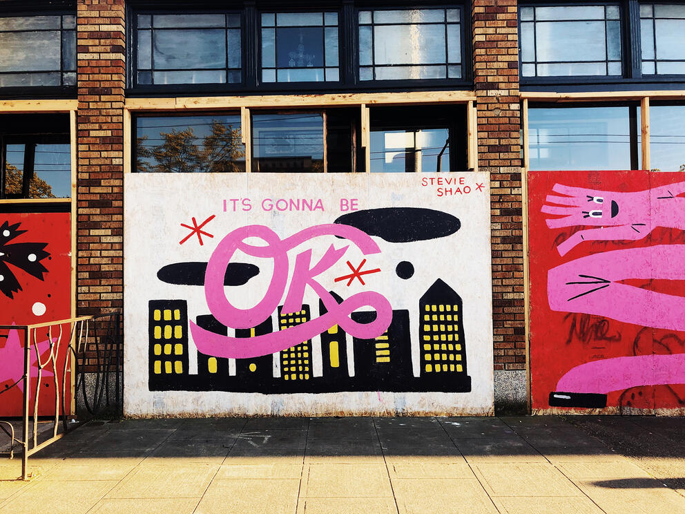 Mural with black downtown image and pink lettering stating: "It's gonna be OK"