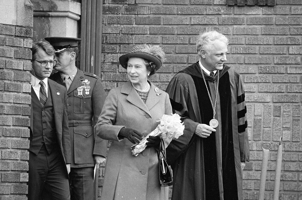 The queen walks arm in arm with a man wearing robes