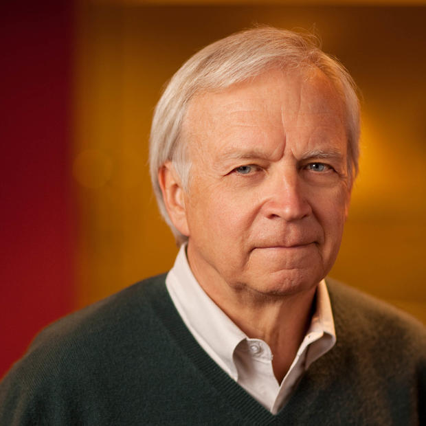 Tom Alberg takes a head shot in front of a orange background