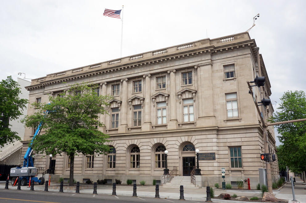 A tan stone court building occupies a tree-lined street corner in Yakima