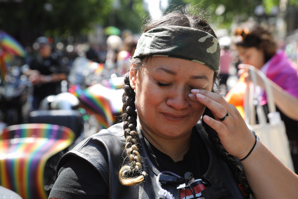 A close up of woman wearing a bandana wiping away a tear