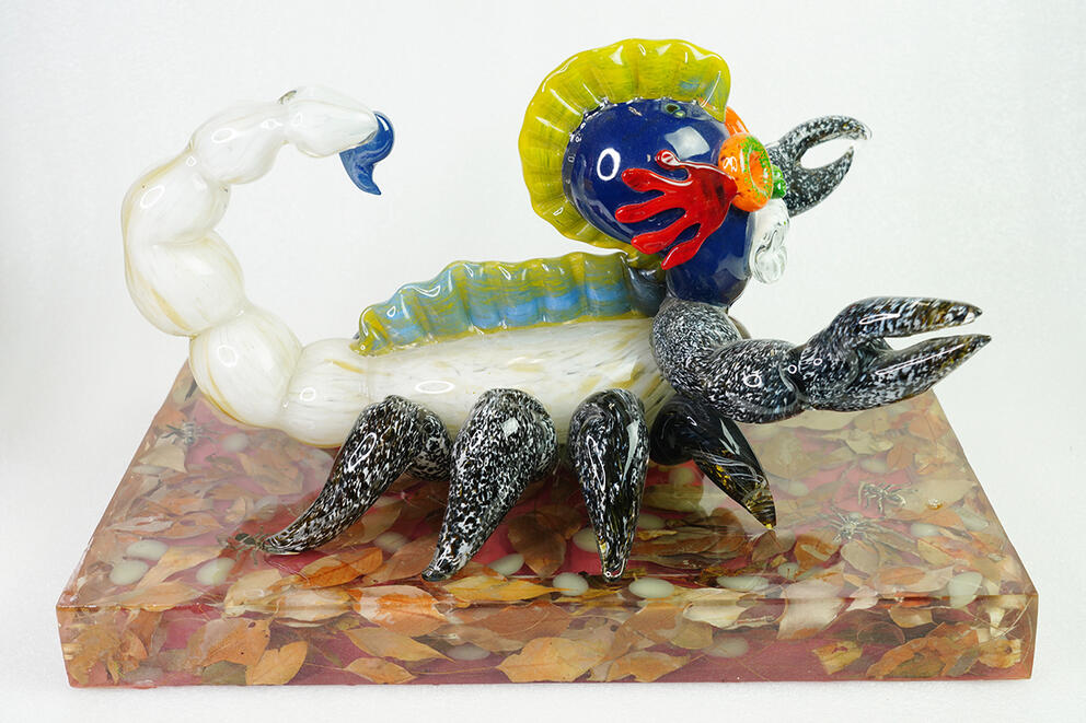a glass figurine depicting a strange scorpion made of glass with black claws